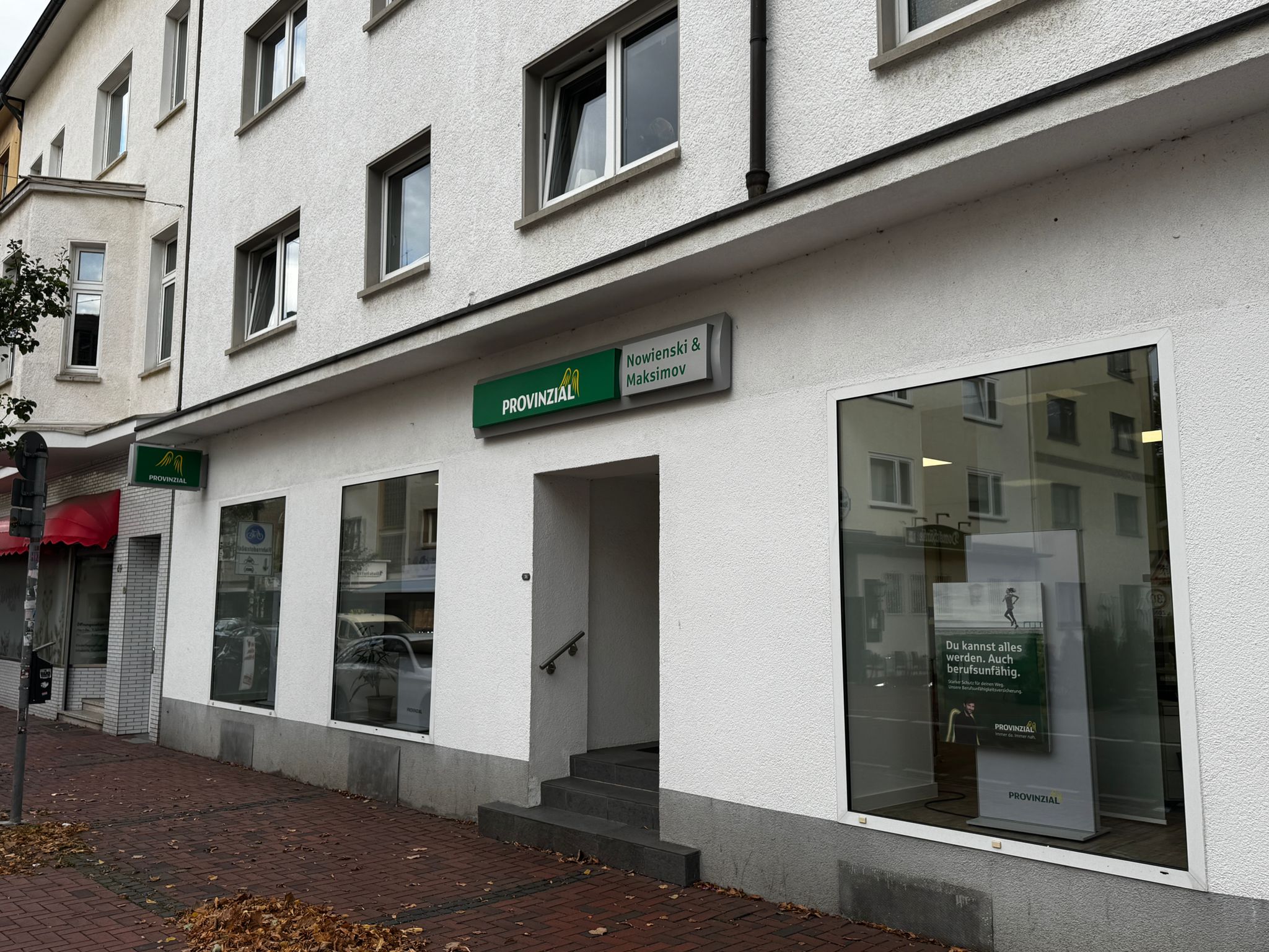 Eine weiße Gebäudefassade mit großen Fenstern und einem grünen Provinzial-Schild.