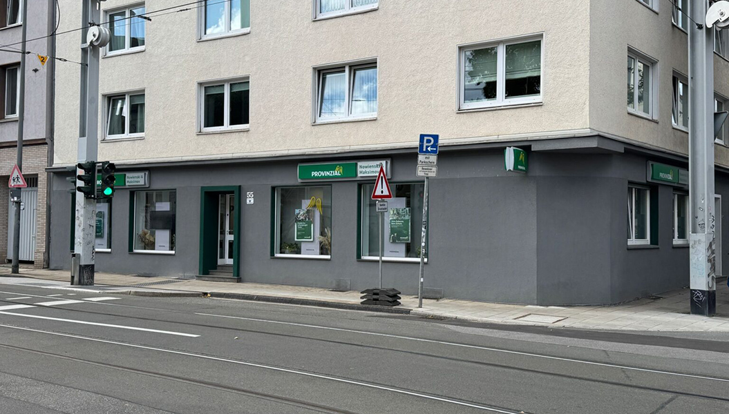Ecke eines hellen Gebäudes mit Provinzial Versicherungsschildern und grüner Ampel