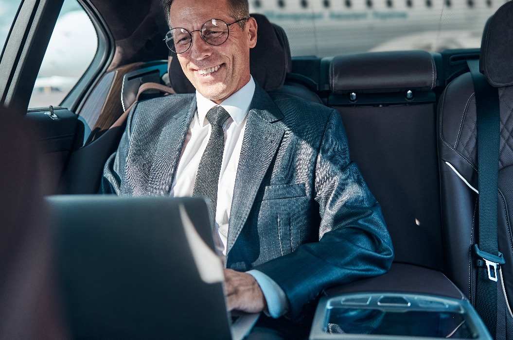 Lächelnder Geschäftsmann mit Laptop im Auto nach der Landung