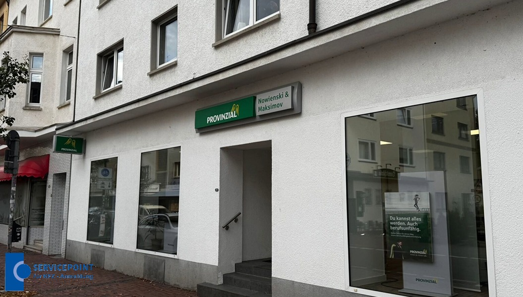 Eine weiße Fassade mit großen Fenstern, Provinzial-Schild und Spiegelung der Straße