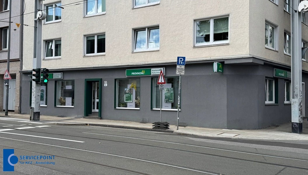 Eckgebäude mit hellgrauer Fassade, mehreren Fenstern und grünen Provinzial-Schildern