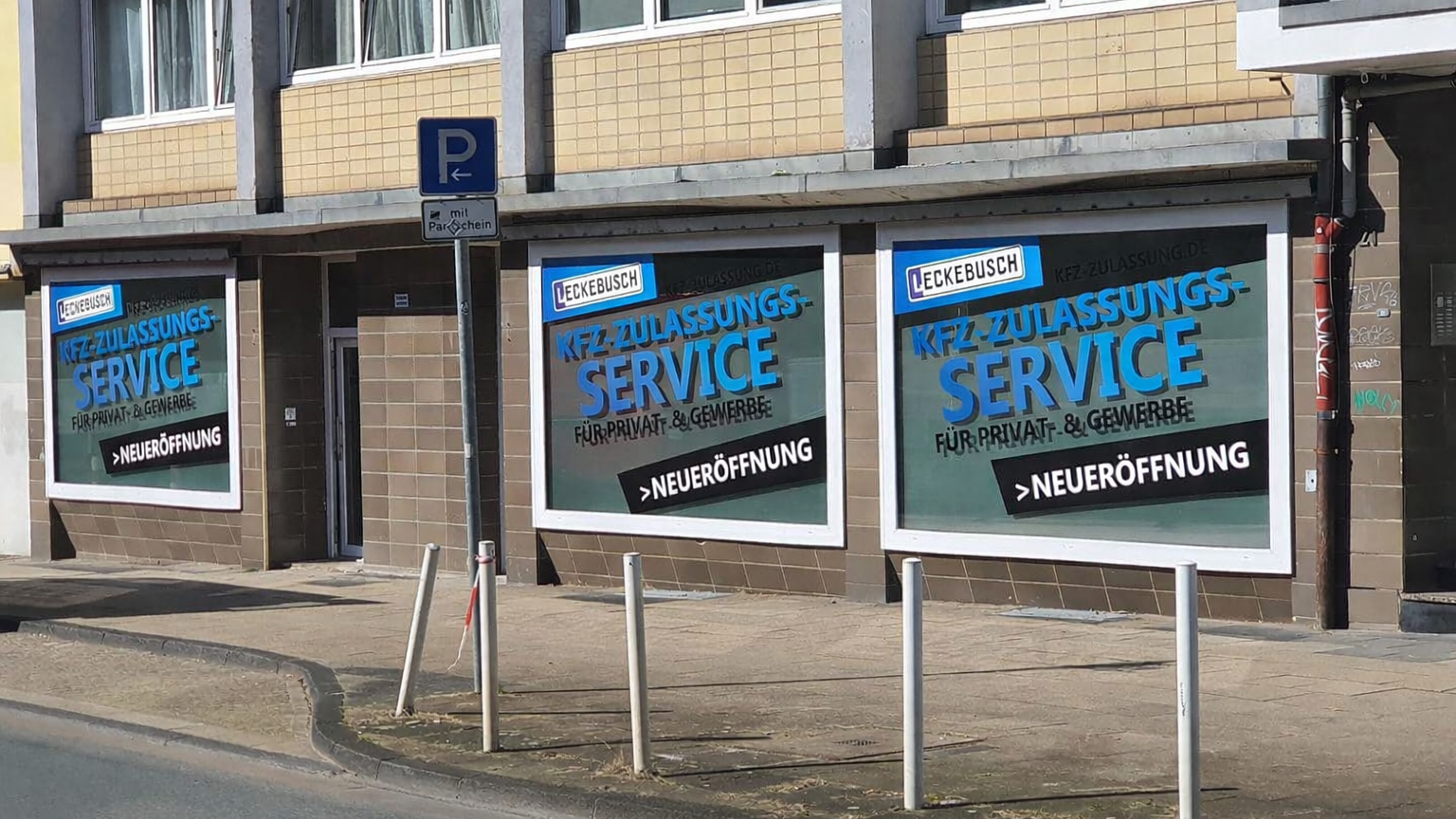 Werbung für KFZ-Zulassungsservice in Blau Weiß mit Neueröffnungs Hinweisen an Gebäudefassade