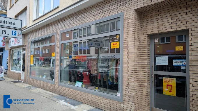 Eine Schaufensterfront mit Kleidungsauslage, brauner Klinkerfassade und gelben Schildern