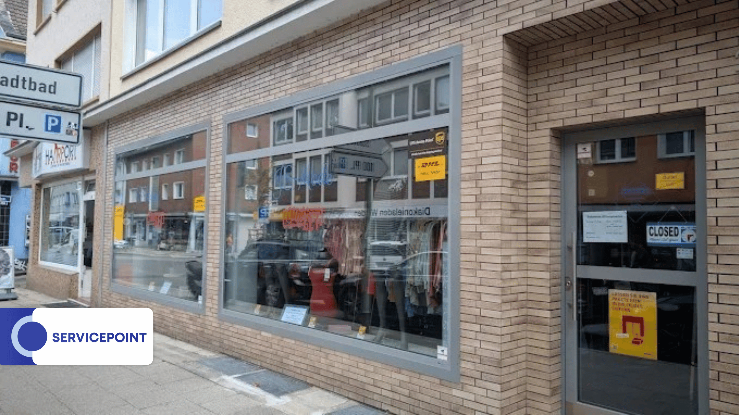 Ein Schaufenster mit reflektierenden Scheiben zeigt Kleidung und gelbe Hinweisschilder